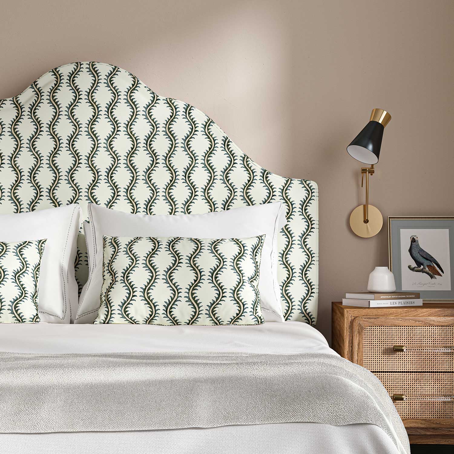 Headboard upholstered in a printed linen fabric sample in green and off white featuring a stylized fern pattern.
