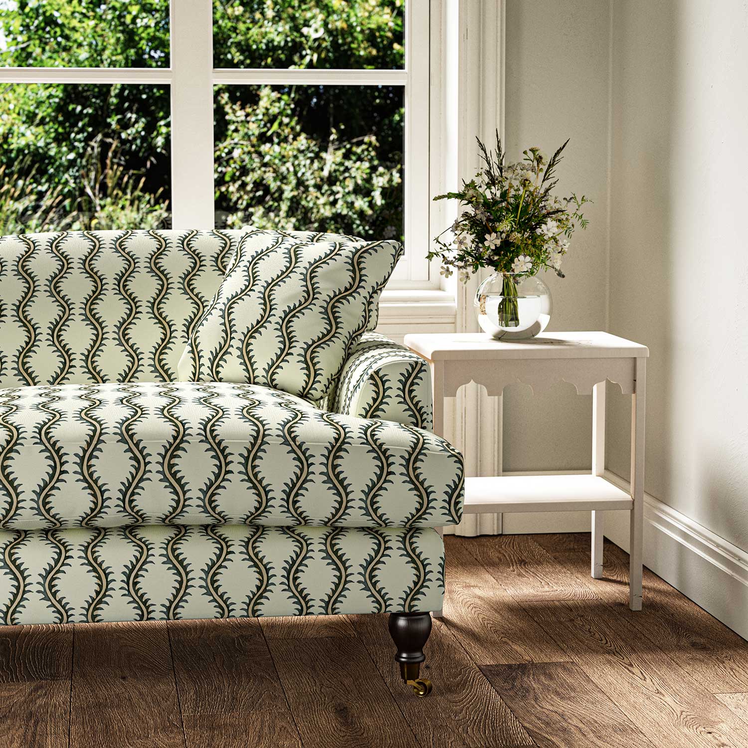 Sofa upholstered in a printed linen fabric sample in green and off white featuring a stylized fern pattern.