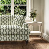 Sofa upholstered in a printed linen fabric sample in green and off white featuring a stylized fern pattern.
