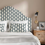 Headboard upholstered in a printed linen fabric sample in blue and off white featuring a stylized fern pattern.