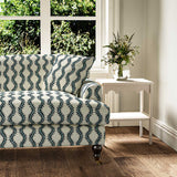 Sofa upholstered in a printed linen fabric sample in blue and off white featuring a stylized fern pattern.