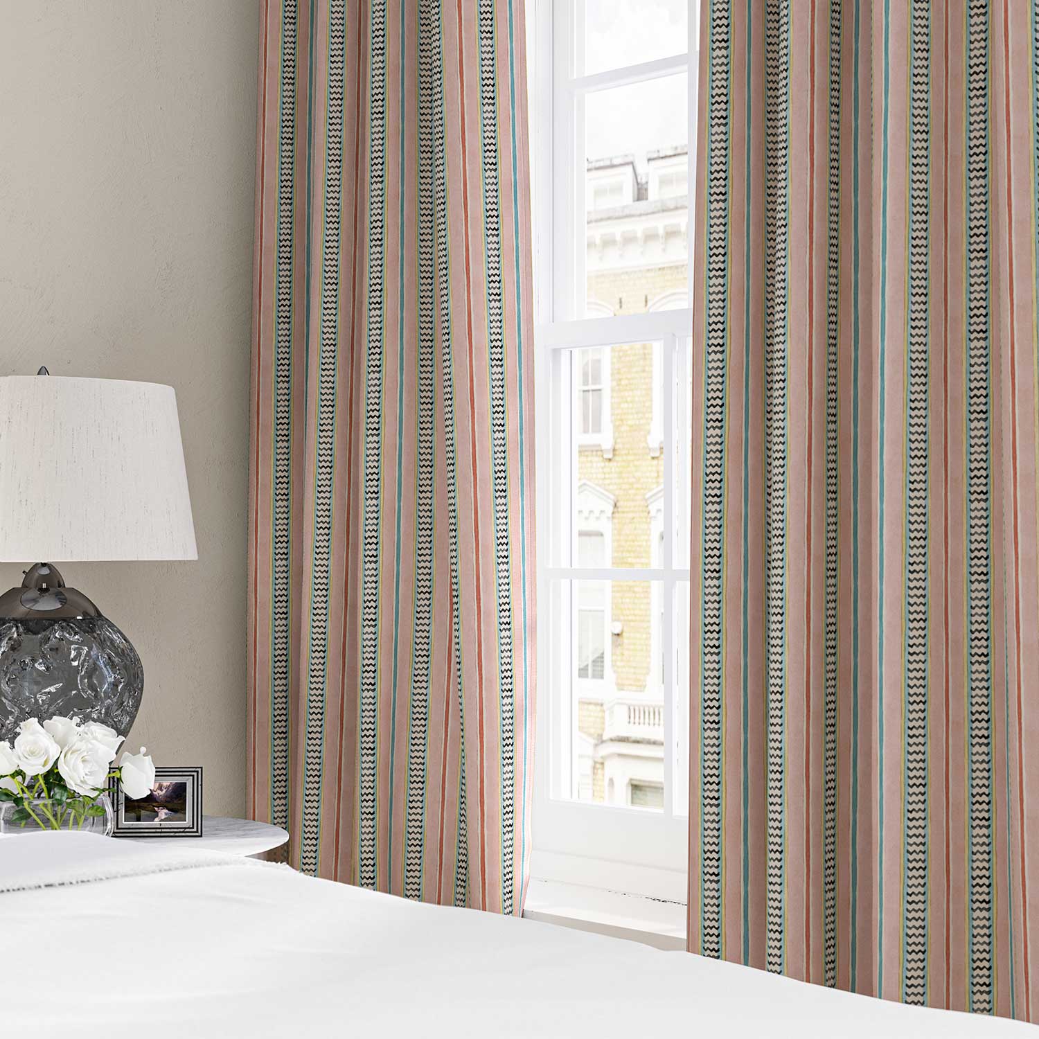 Curtains in a multicoloured – pink, red and blue – printed linen fabric featuring stripes, wavy edges and zigzags.