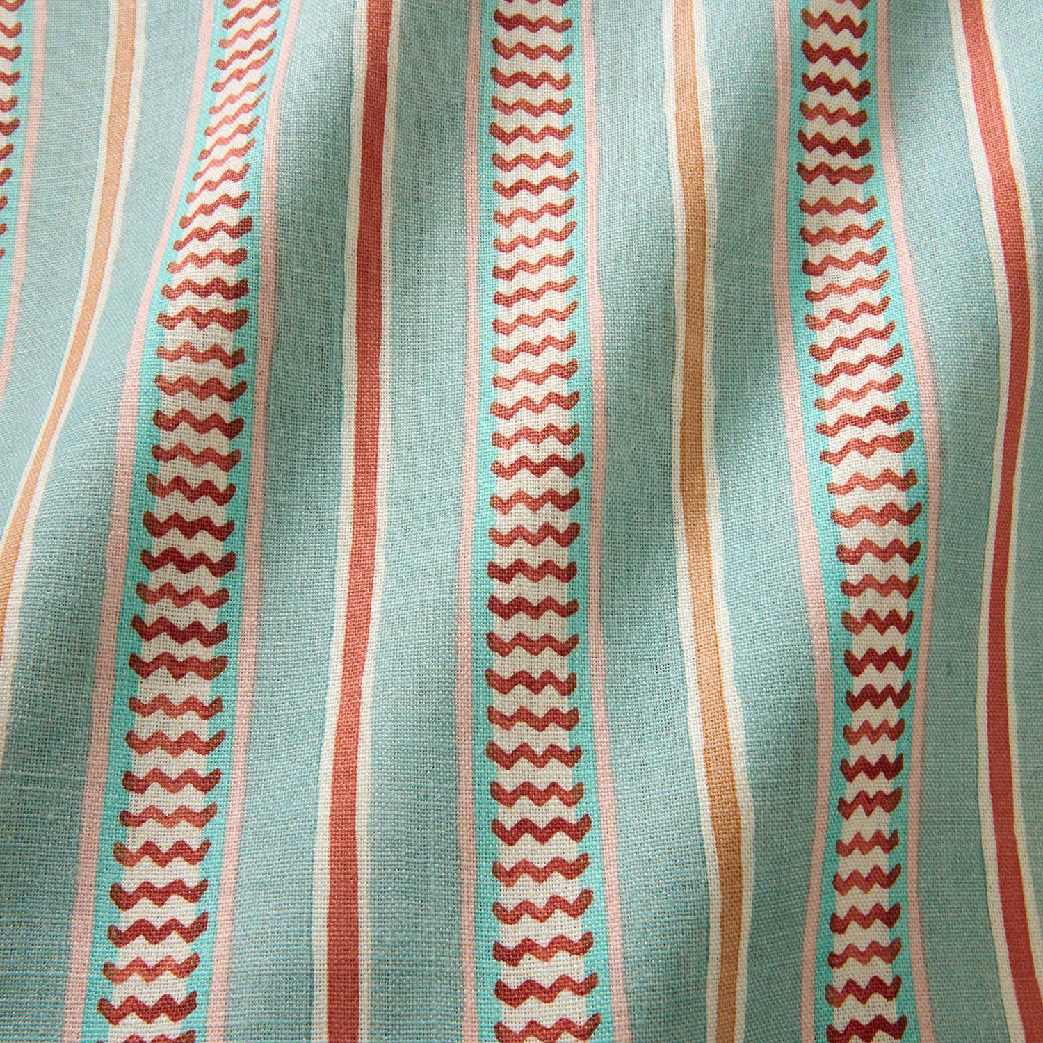 A multicoloured – blue, red and pink – printed linen fabric sample featuring stripes, wavy edges and zigzags.