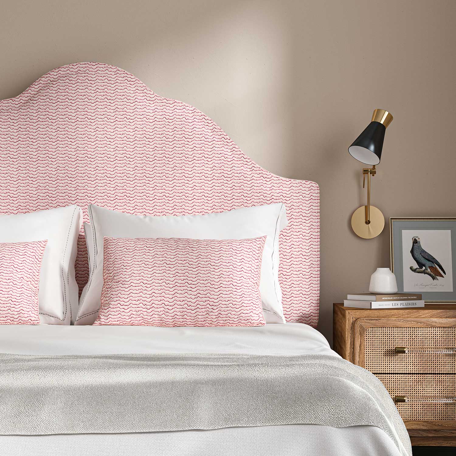 Headboard upholstered in a printed linen fabric sample in pink, red and off white featuring a sound wave pattern