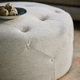 Woven light neutral coloured fabric on a ottoman