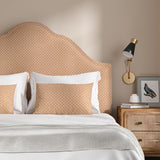 Headboard upholstered in a orange and off-white woven fabric featuring a trellis pattern.