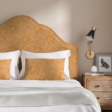 Headboard upholstered in a orange and off-white woven fabric featuring a geometric pattern.