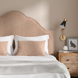 Headboard upholstered in a pink and off-white woven fabric featuring a wavy pattern.