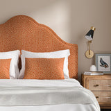 Headboard upholstered in a orange and off-white woven fabric featuring a wavy pattern.