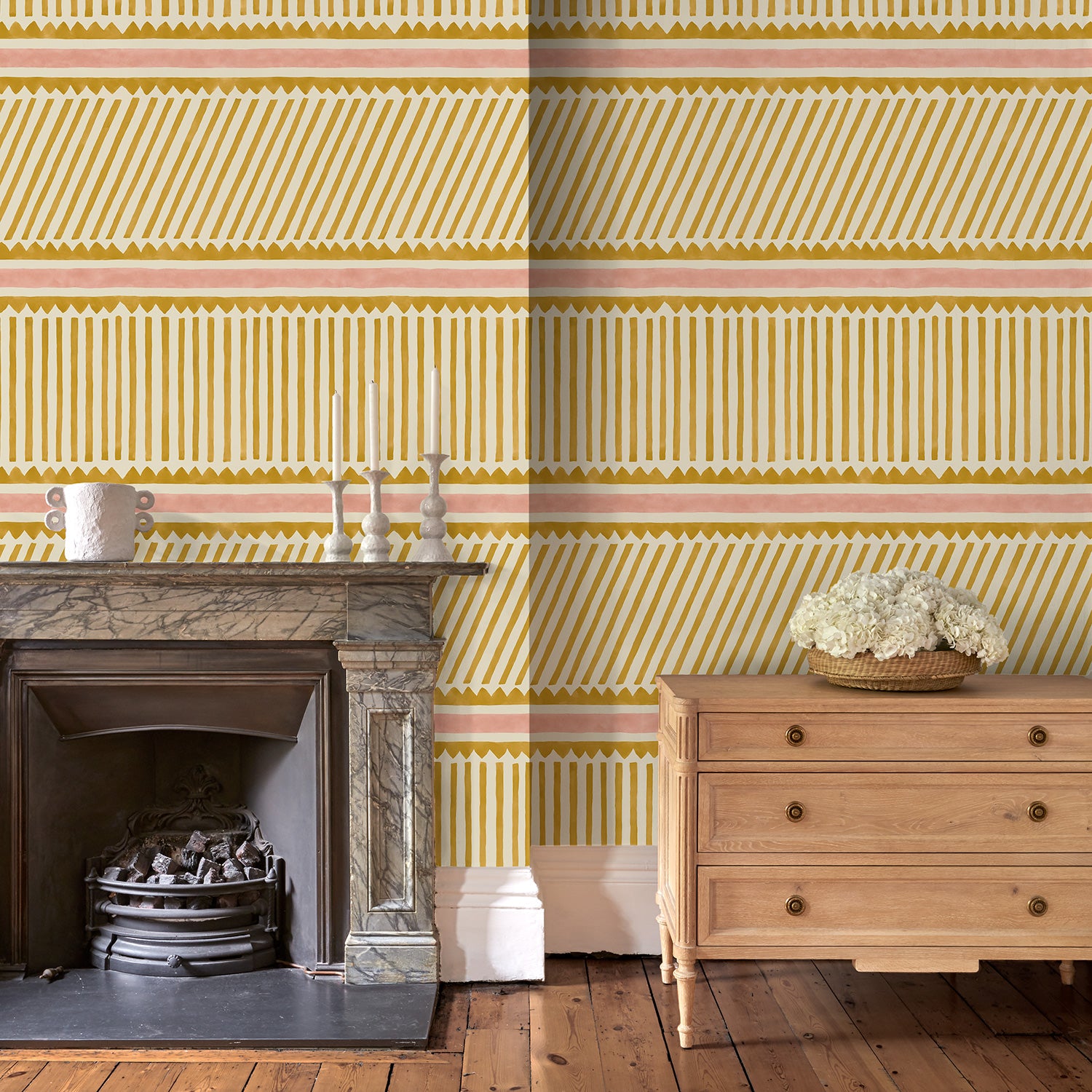 Living room with playful gold and pink wallpaper with a combination of tonal stripes, zigzags, and matching colour bands.