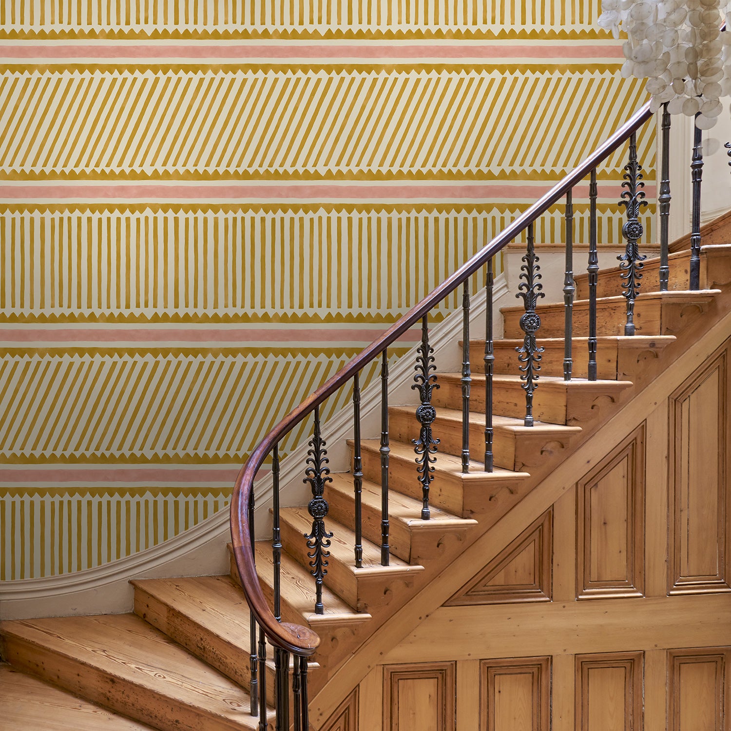Hall with playful gold and pink wallpaper with a combination of tonal stripes, zigzags, and matching colour bands.