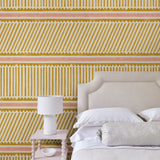 Bedroom with playful gold and pink wallpaper with a combination of tonal stripes, zigzags, and matching colour bands.