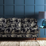 Sofa covered in a printed velvet fabric featuring a rich, tropical-style toile in dark grey.
