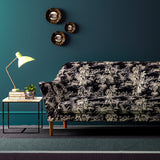 Sofa covered in a printed velvet fabric featuring a rich, tropical-style toile in dark grey.