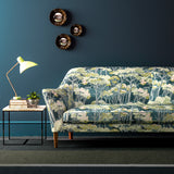 Sofa covered in a printed velvet upholstery fabric showcasing a blue/green Japanese tree design.