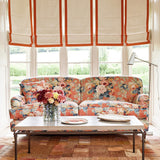 Sofa covered in a printed linen fabric with bouquets of roses on an orange backdrop.