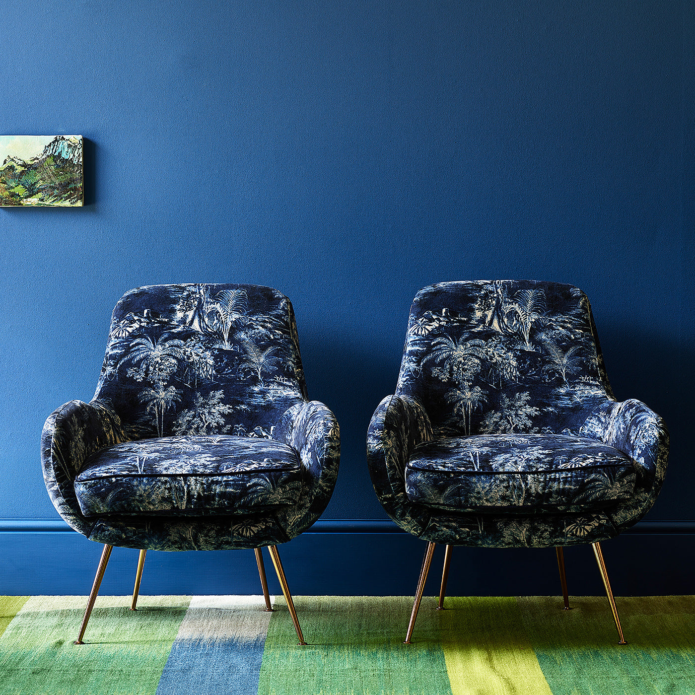 Two chairs covered in a printed velvet fabric showcasing a rich, tropical-style toile in Indigo.