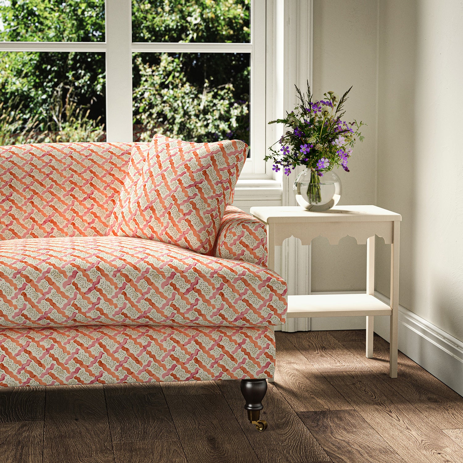 Printed linen fabric - a contemporary lattice design in red, pink, cream and white – on a sofa