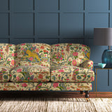 A printed velvet fabric depicts a menagerie of parrots, lions, and alluring flowers in cream on an sofa