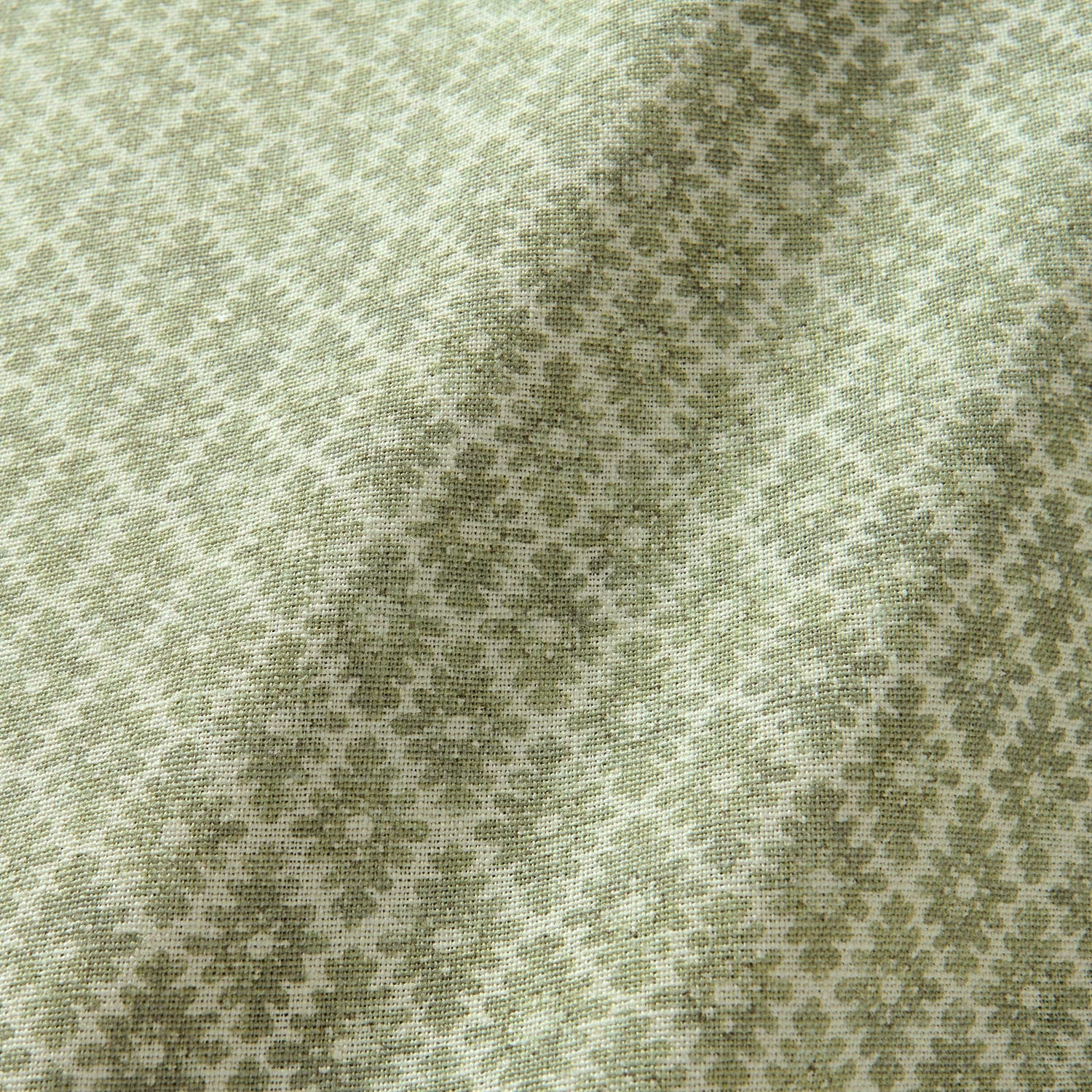 Fabric sample of a green and neutral printed linen fabric with a geometric pattern