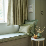 Curtains, window seat and cushions in a green and neutral printed linen fabric with a geometric pattern