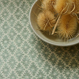 Fabric sample of a green and neutral printed linen fabric with a geometric pattern