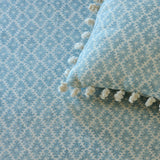 Cushion in a blue and neutral printed linen fabric with a geometric pattern