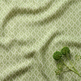 Fabric sample of a green and neutral printed linen fabric with a geometric pattern