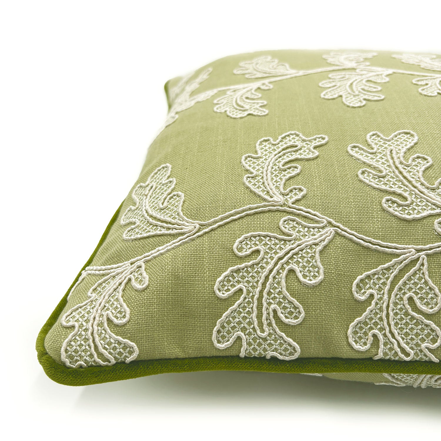 Green embroidered cushion with white leaf pattern.