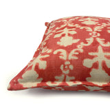 Decorative pillow with red and ivory floral pattern.