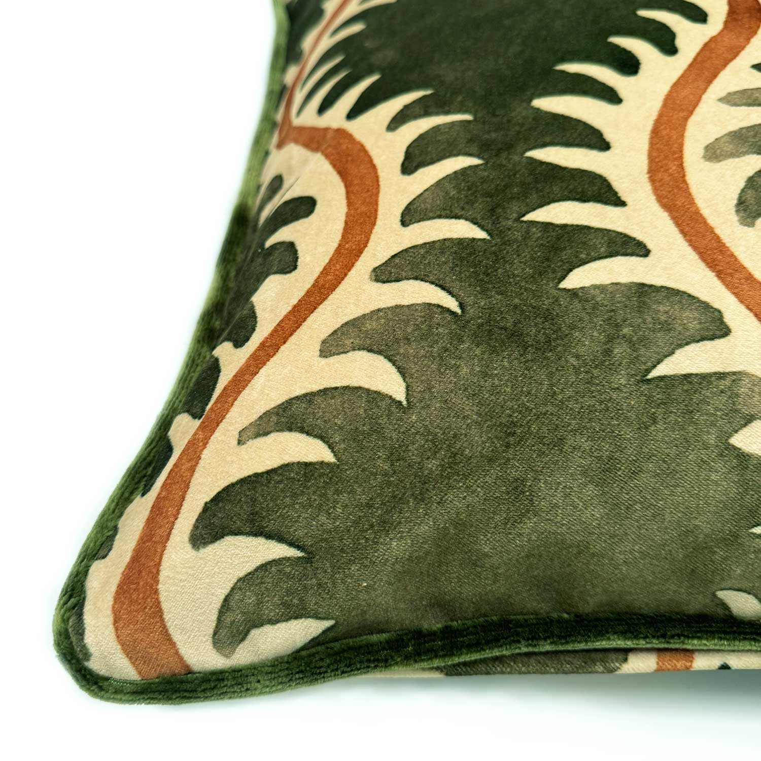 A green, orange and off white velvet cushion with a all-over repeat pattern and velvet piping.