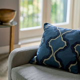 A blue and off white linen cushion featuring a mirrored ribbon pattern with a velvet piping.