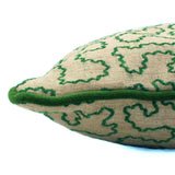 A green and off white woven cushion featuring a wavy pattern with a velvet piping.