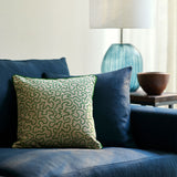 A green and off white woven cushion featuring a wavy pattern with a velvet piping.