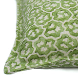 A green and cream linen cushion with a block print pattern.