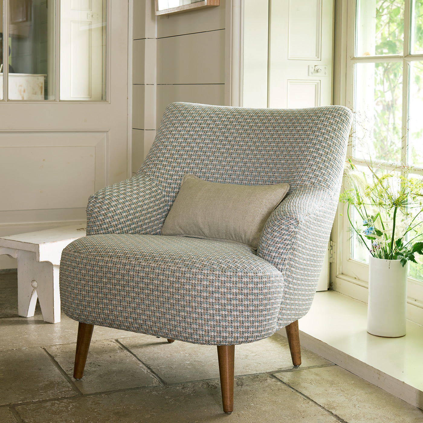 Armchair in a printed linen fabric with textural weave pattern in brown and blue colours.