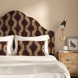 Headboard upholstered in a printed velvet fabric in purple and orange featuring a stylized fern pattern.