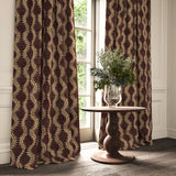 Curtains in a printed velvet fabric in purple and orange featuring a stylized fern pattern.