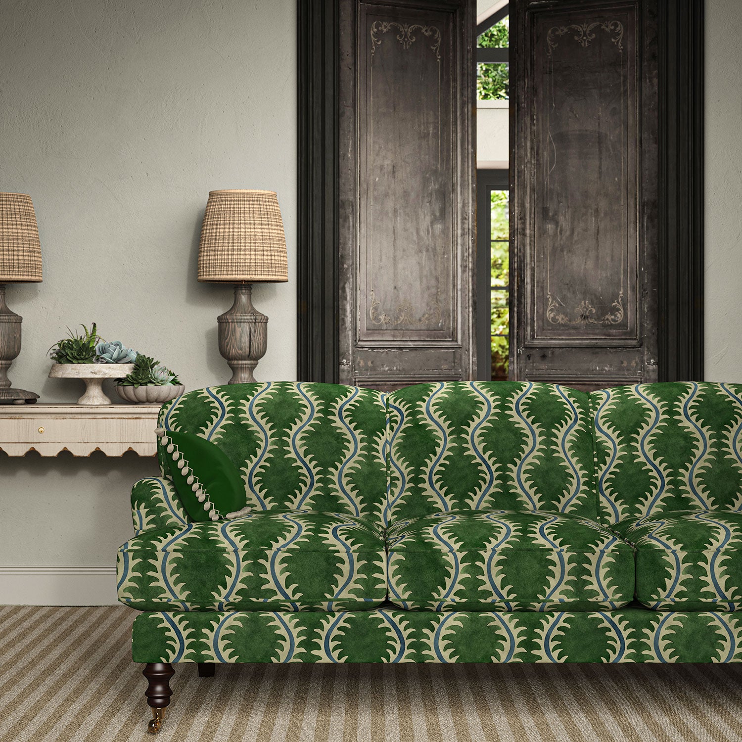 Sofa upholstered in a printed velvet fabric in green and blue featuring a stylized fern pattern.