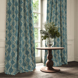 Curtains in a printed velvet fabric in blue and off white featuring a stylized fern pattern.