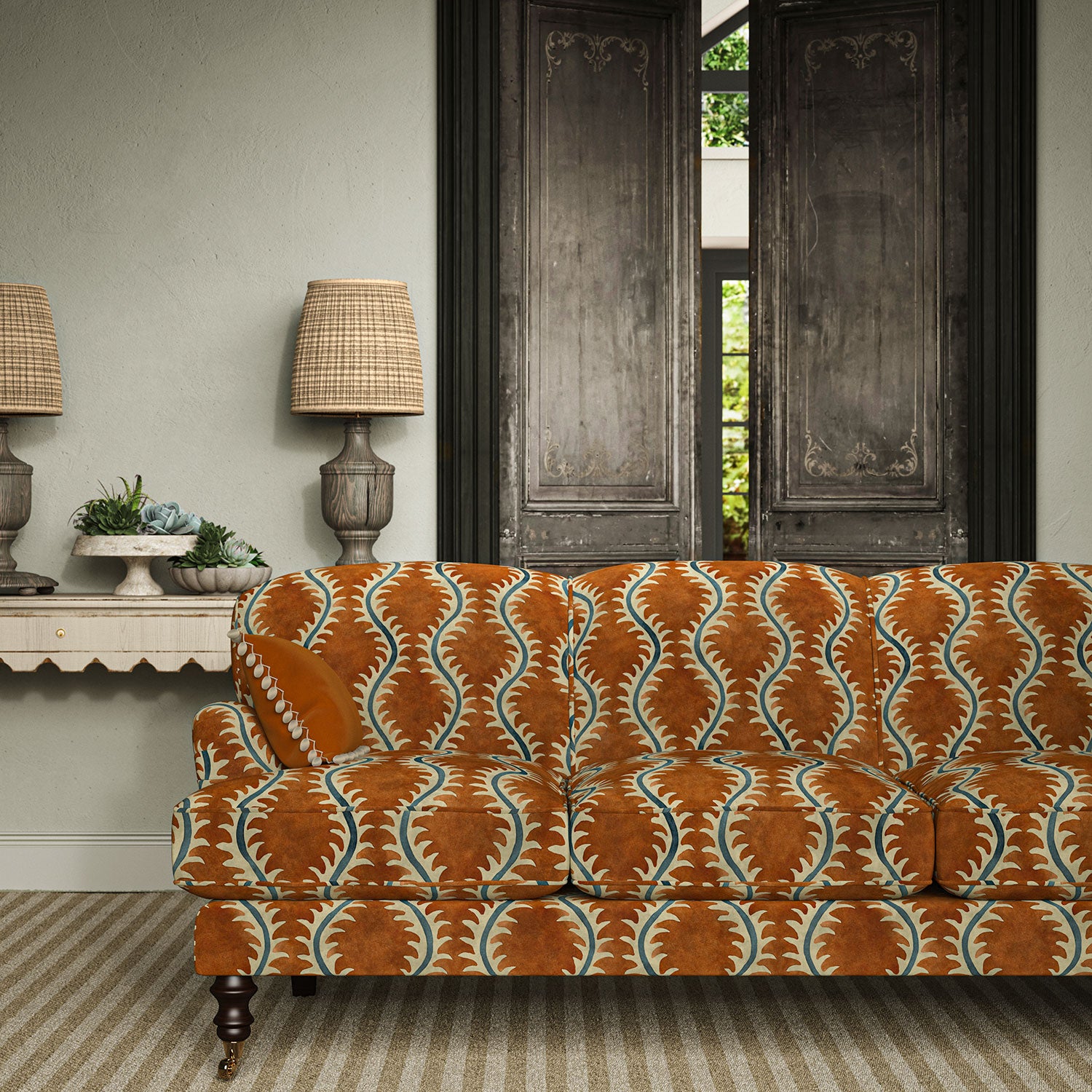 Sofa upholstered in a printed velvet fabric in orange and blue featuring a stylized fern pattern.