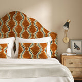 Headboard upholstered in a printed velvet fabric in orange and blue featuring a stylized fern pattern.