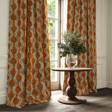 Curtains in a printed velvet fabric in orange and blue featuring a stylized fern pattern.