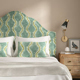 Headboard upholstered in a printed velvet fabric in blue and green featuring a stylized fern pattern.