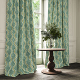 Curtains in a printed velvet fabric in blue and green featuring a stylized fern pattern.