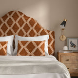 Bedroom with a curved upholstered headboard covered in ginger/brown printed velvet featuring an irregular diamond motif.
