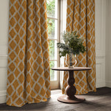Brown and blue printed velvet curtains with an irregular diamond pattern framing a tall window.