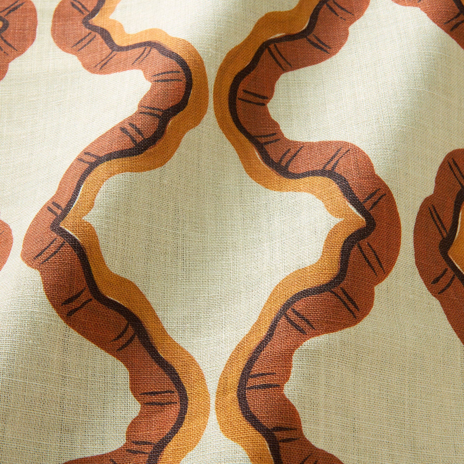 A printed linen fabric sample in orange, brown, and off white featuring a mirrored ribbon pattern.