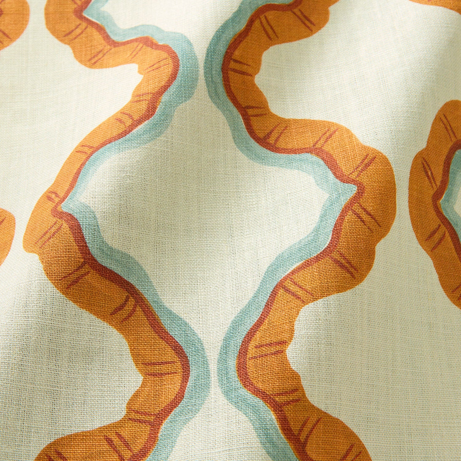 A printed linen fabric sample in blue, orange, and off white featuring a mirrored ribbon pattern.