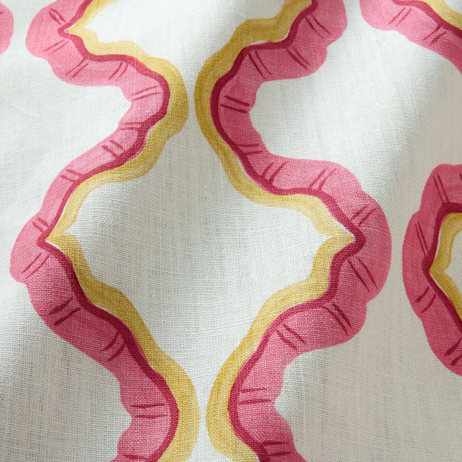 A printed linen fabric sample in pink, yellow, and off white featuring a mirrored ribbon pattern.